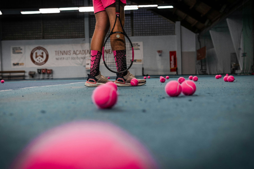 Tennis player practing with pink tennis balls